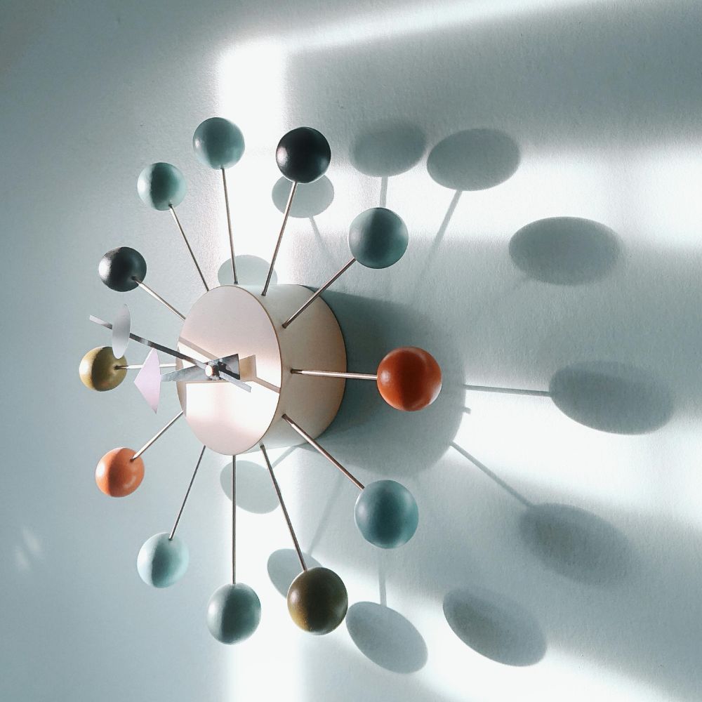 Modern wall clock with colorful spherical design on a light background

